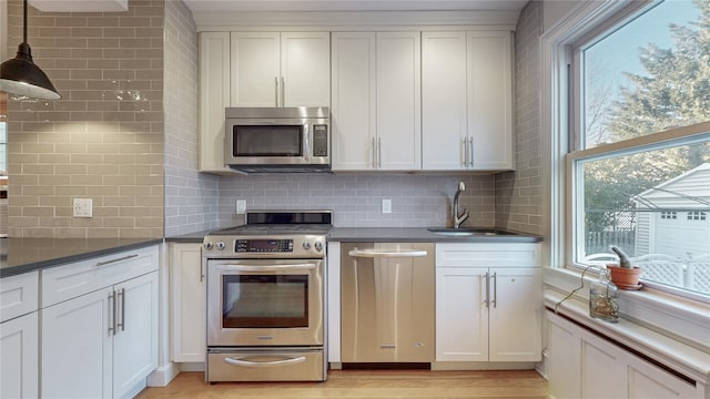 kitchen with stainless steel appliances, light wood-type flooring, a sink, and a healthy amount of sunlight