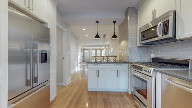 kitchen featuring dark countertops, light wood finished floors, appliances with stainless steel finishes, and backsplash