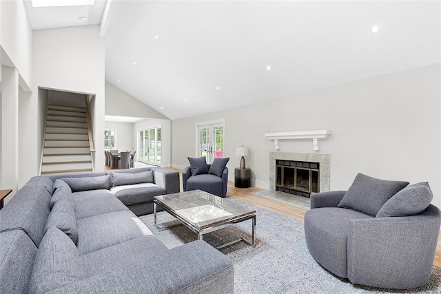 living room with a fireplace, light hardwood / wood-style flooring, and high vaulted ceiling