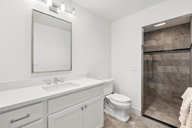 bathroom featuring a tile shower, vanity, and toilet