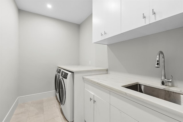 laundry area with sink, light tile patterned floors, washing machine and dryer, and cabinets