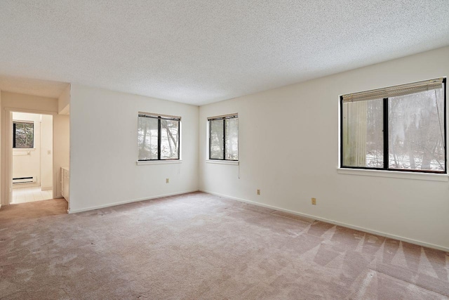 carpeted spare room featuring baseboard heating and a textured ceiling