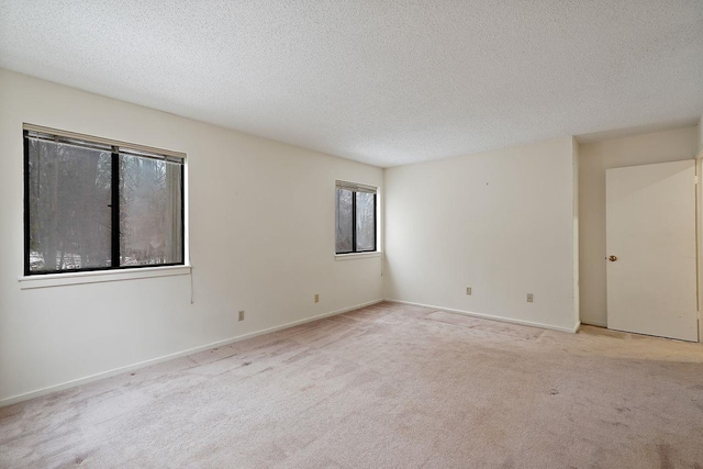 spare room with light colored carpet and a textured ceiling