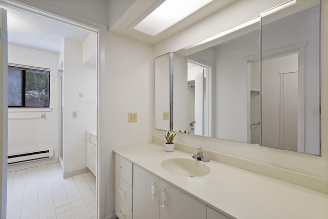 bathroom with baseboard heating, tile patterned floors, vanity, and walk in shower