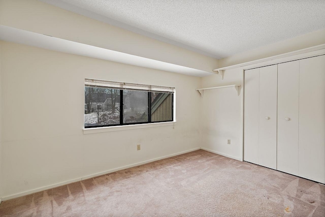 unfurnished bedroom with a closet, light carpet, and a textured ceiling