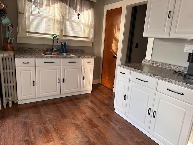 kitchen featuring white cabinetry, radiator, sink, and dark hardwood / wood-style flooring