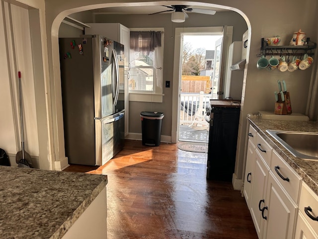 kitchen with dark wood finished floors, dark countertops, a ceiling fan, freestanding refrigerator, and white cabinetry