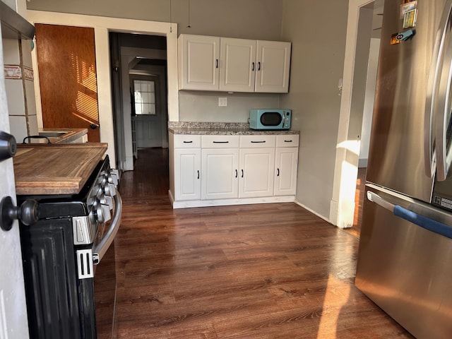 kitchen with stainless steel appliances, baseboards, white cabinetry, and dark wood-type flooring