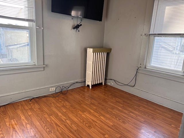 spare room with radiator heating unit and wood finished floors