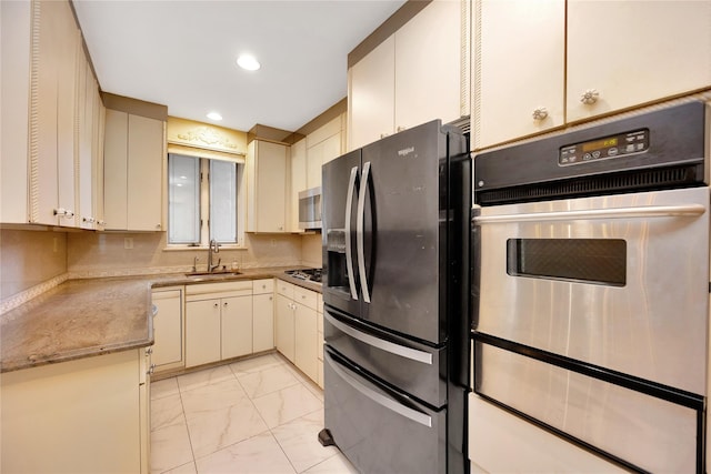 kitchen featuring marble finish floor, cream cabinets, stainless steel appliances, a sink, and recessed lighting