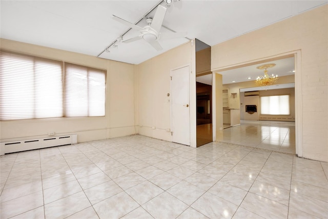 empty room with a baseboard heating unit, rail lighting, light tile patterned flooring, and ceiling fan with notable chandelier