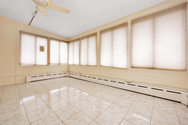 empty room featuring light tile patterned floors, baseboard heating, and a ceiling fan