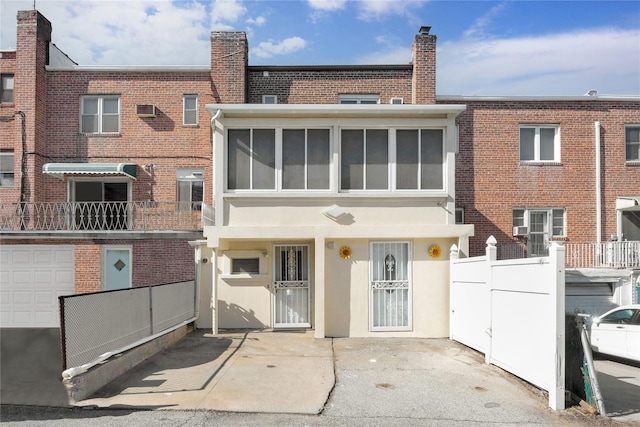 rear view of property featuring brick siding, fence, a wall mounted AC, and stucco siding