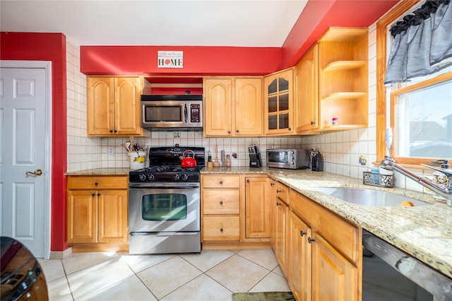 kitchen featuring light stone counters, stainless steel appliances, sink, and backsplash