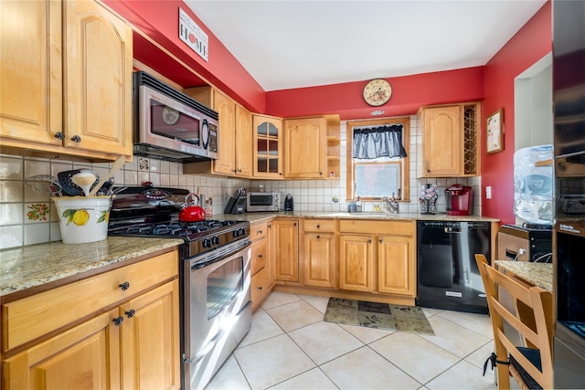 kitchen with light tile patterned flooring, sink, light stone counters, appliances with stainless steel finishes, and decorative backsplash