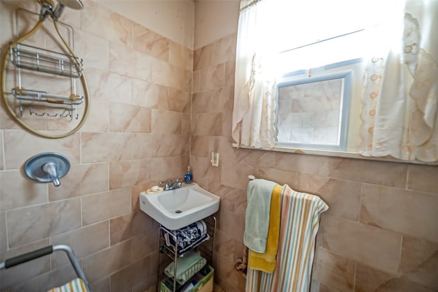 bathroom with a sink, tiled shower, and tile walls