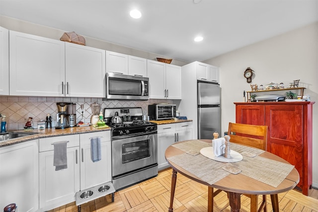 kitchen featuring appliances with stainless steel finishes, sink, decorative backsplash, and white cabinets