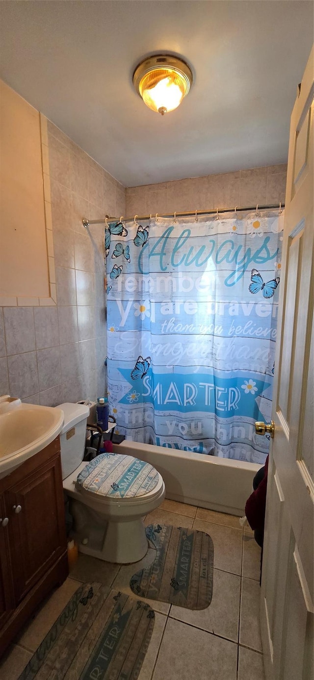 full bathroom featuring tile patterned floors, toilet, tile walls, shower / tub combo, and vanity
