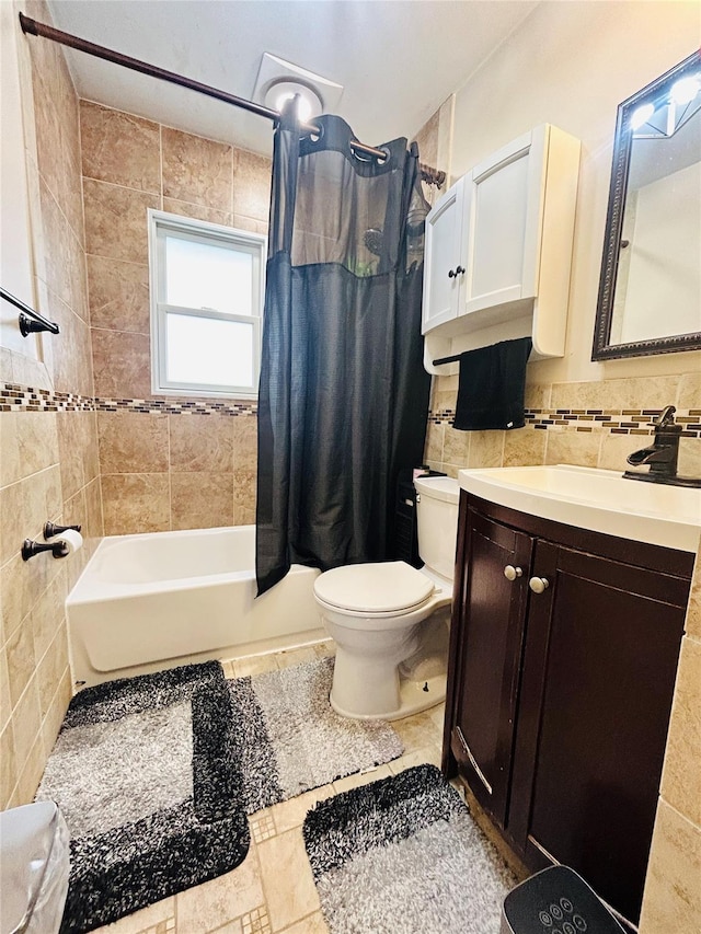 full bathroom with shower / tub combo with curtain, tile walls, tile patterned flooring, vanity, and toilet