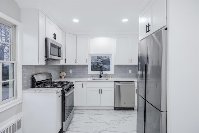 kitchen featuring white cabinetry, stainless steel appliances, radiator, and sink