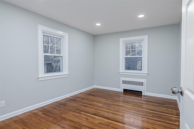 empty room featuring radiator heating unit and dark hardwood / wood-style flooring