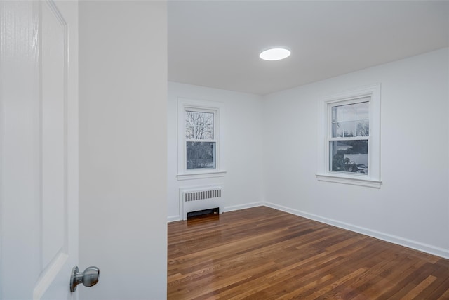 spare room featuring dark hardwood / wood-style flooring and radiator heating unit