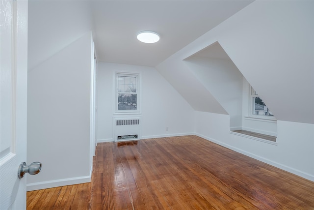 additional living space with lofted ceiling, radiator, and hardwood / wood-style floors