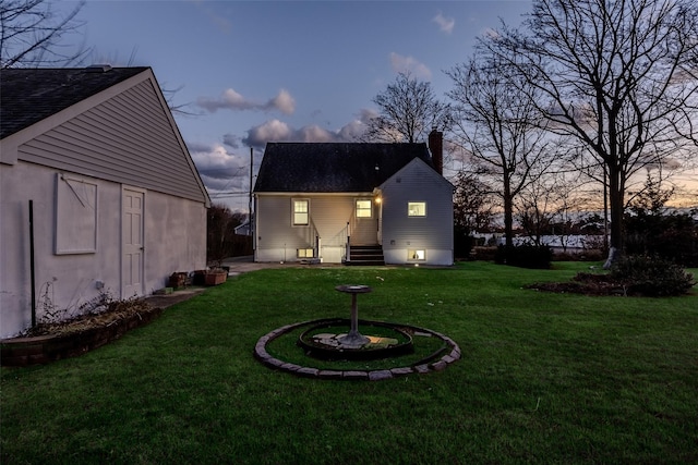 back house at dusk featuring a yard