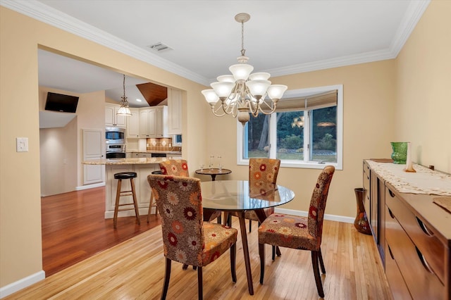 dining area with crown molding, a chandelier, and light hardwood / wood-style flooring