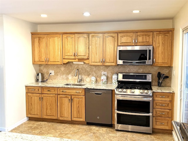 kitchen featuring sink, backsplash, stainless steel appliances, and light stone countertops