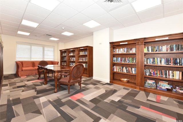 dining space featuring a drop ceiling and dark colored carpet