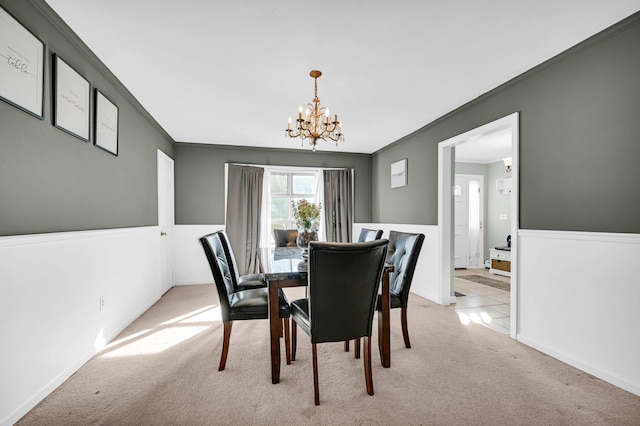 dining space with light carpet, ornamental molding, and a notable chandelier