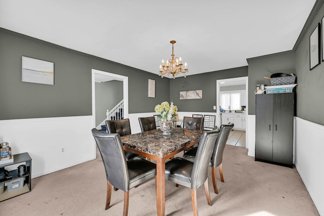 dining space featuring light colored carpet, stairway, and an inviting chandelier