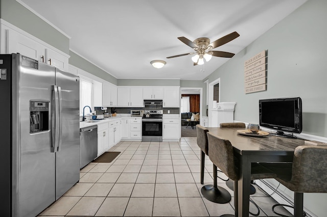 kitchen with stainless steel appliances, white cabinets, light tile patterned flooring, a sink, and under cabinet range hood