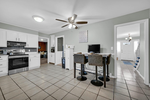 kitchen featuring backsplash, stainless steel range with electric cooktop, under cabinet range hood, and light tile patterned floors