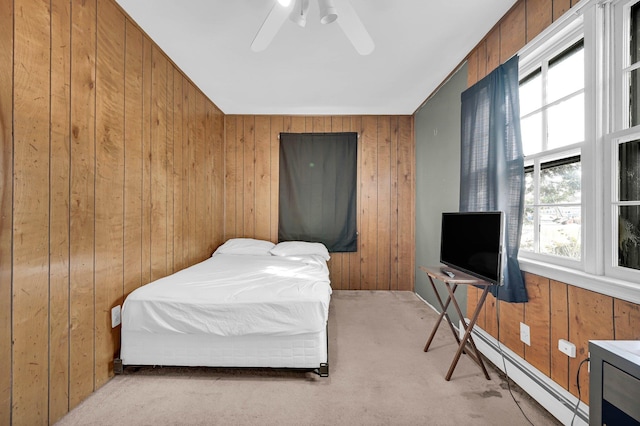 carpeted bedroom with wood walls, ceiling fan, and a baseboard heating unit