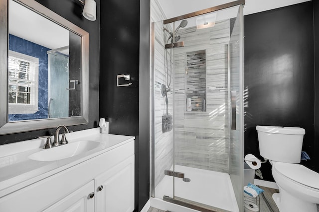 full bath with a stall shower, vanity, toilet, and baseboards