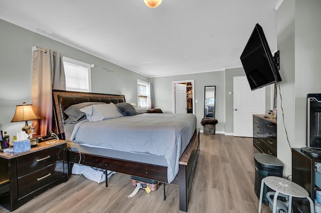 bedroom featuring ornamental molding, light wood-type flooring, a closet, and baseboards