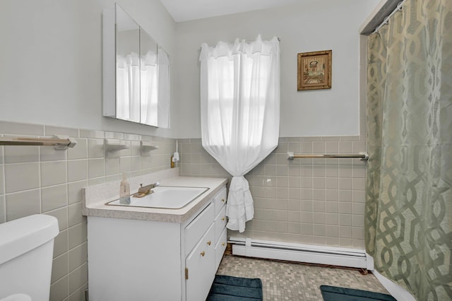 full bath featuring wainscoting, toilet, vanity, a baseboard heating unit, and tile walls