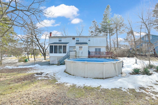 snow covered property featuring a deck, a chimney, a sunroom, and an outdoor pool