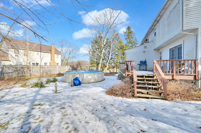 yard layered in snow featuring fence, a deck, and a fenced in pool