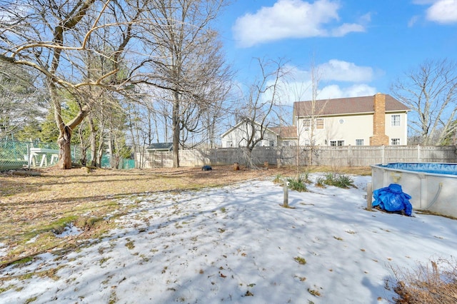 yard covered in snow with a fenced in pool and a fenced backyard