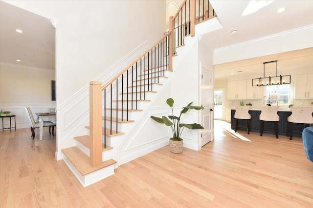 stairway featuring hardwood / wood-style flooring, crown molding, and a notable chandelier