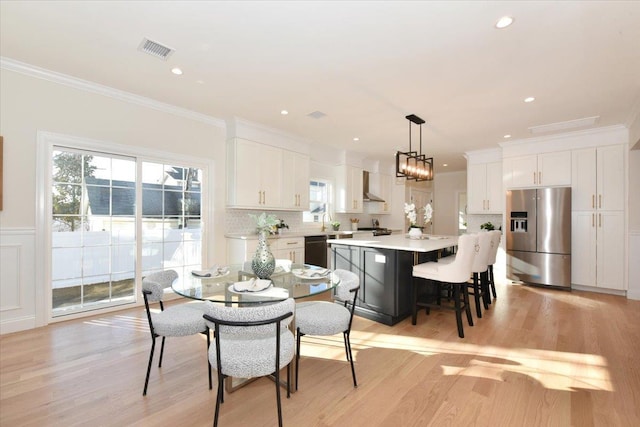 dining room featuring light hardwood / wood-style flooring, plenty of natural light, and ornamental molding