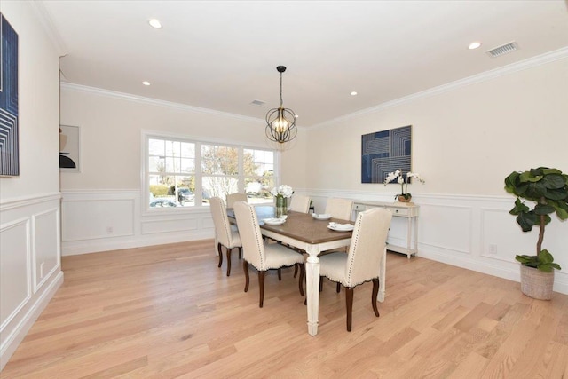 dining space featuring crown molding, a chandelier, and light wood-type flooring