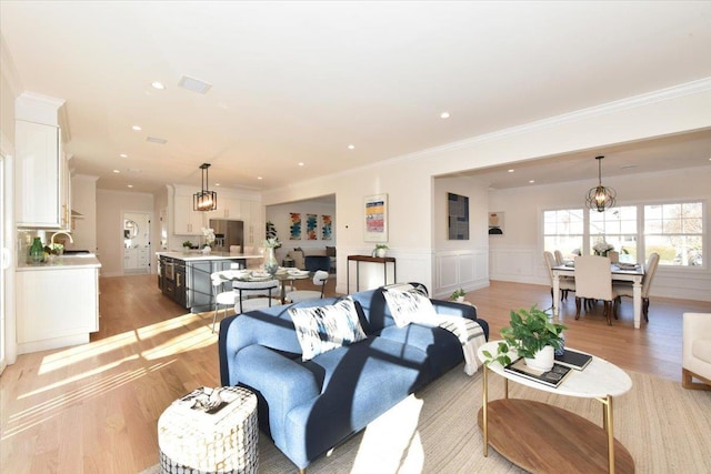 living room featuring crown molding, sink, and light wood-type flooring