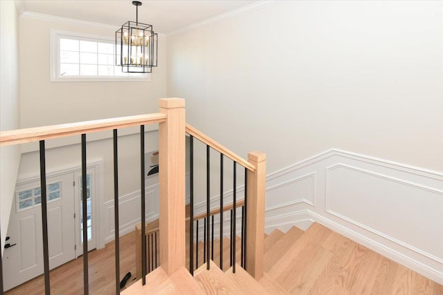 stairs with wood-type flooring, a chandelier, and crown molding