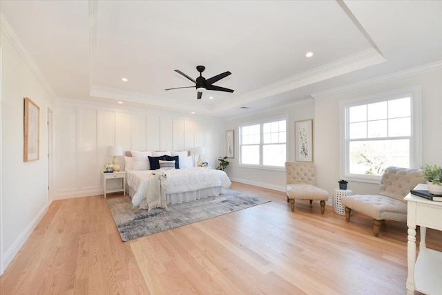 bedroom with a raised ceiling, crown molding, ceiling fan, and light wood-type flooring