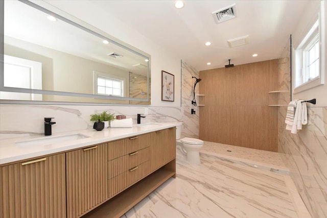 bathroom featuring a tile shower, vanity, tile walls, and toilet