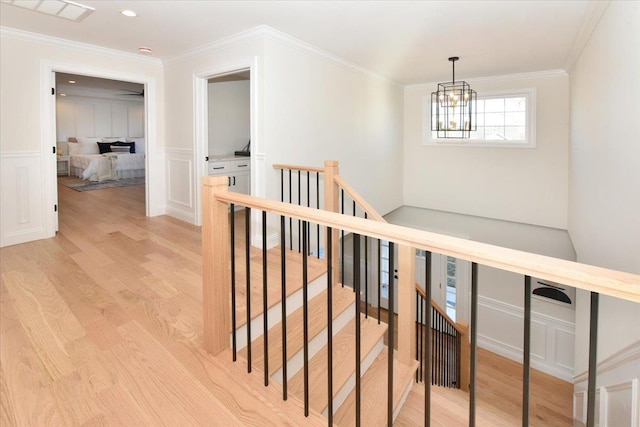 corridor featuring ornamental molding, an inviting chandelier, and light wood-type flooring